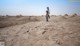 A man standing on top of a dirt field.