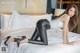 A woman in black leather pants and high heels on a bed.