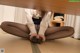 A woman in a white shirt and black pantyhose sitting under a table.