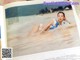 A woman in a blue bikini laying in the water.