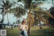 A woman standing in front of a palm tree in a park.