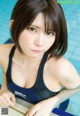 A woman in a black and blue bathing suit sitting by a pool.