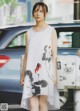 A woman in a white dress standing next to a car.