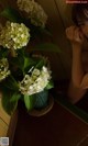 A woman sitting in front of a vase of white flowers.