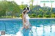 A woman in a white swimsuit and hat standing in a pool.