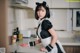 A woman in a maid outfit standing in a kitchen.