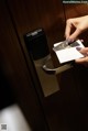 A person opening a door with a card in their hand.