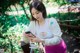 A woman in a white top and pink pants looking at her phone.