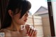 A woman with long black hair and red nails looking out a window.