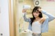 A woman blow drying her hair in front of a mirror.